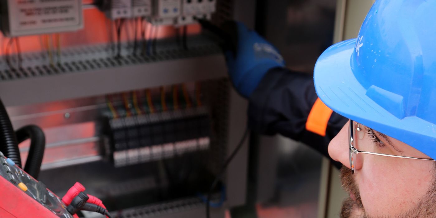 Technik w kasku i odzieży ochronnej podczas kontroli instalacji budynku